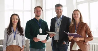 Mutlu iş adamlarının portresi, kimlik kartı takan atölye katılımcıları kapalı alanda poz veriyor, kameraya bakıyor, kurumsal eğitime, profesyonel toplantıya veya konferansa başarılı bir şekilde katılmayı temsil ediyor