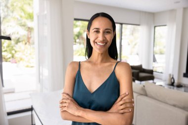 Pozitif güzel genç Maori kadın şık bir dairede duruyor, otel takımı, el ele tutuşup güven jesti yapıyor, kameraya bakıyor, yeni evde boş vakitlerin tadını çıkarıyor, portre için poz veriyor.