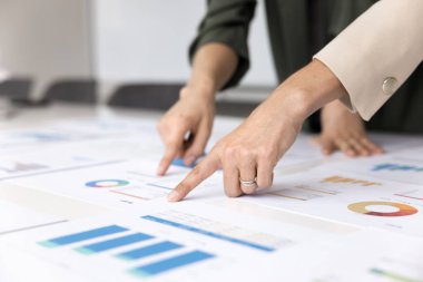 Finans pastası grafiklerine ve bar grafiklerine işaret eden iki iş kadınının eli kapanıyor. Belgeleri gözden geçiriyorlar, iş ortaklığı toplantılarına katılıyorlar, stratejik planlama yapıyorlar. Analiz ve takım çalışması