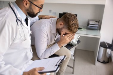 Kötü haberi dikkatle vermek. Empatik genç doktor, kritik teşhis konulduktan sonra avuçlarında saklanan erkek hastayı rahatlatıyor. Duygusal destek sağlıyor. Boşluğu kopyala