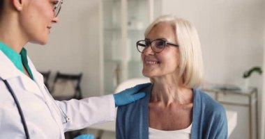 Kauçuk eldivenli kadın endokrinoloji doktorunu kapat, boyuna dokun, klinikteki sağlık kontrolü sırasında orta yaşlı kadın lenf düğümlerini incele. Yetişkin hasta bakımı, teşhis prosedürleri.