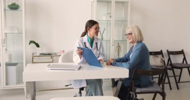 Doktor, panodaki teşhis veya tıbbi sonuçları orta yaşlı kadın hastaya açıklıyor, tedavi planını gözden geçiriyor ve hastaneye yaptığı ziyarette profesyonel tavsiyelerde bulunuyor. Sağlık hizmetleri danışmanlığı