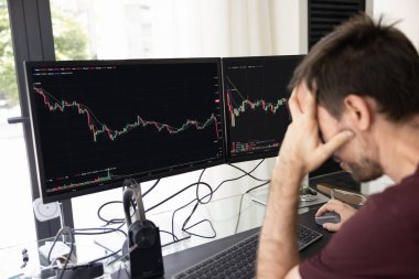 Serbest çalışan tüccar kötü hissediyor ve borsa düşüşü, borsa düşüşü, borsada kaybetmek, finansal düşüş grafikleriyle iki büyük monitörde çalışmak, umutsuzluğa kapılmak.