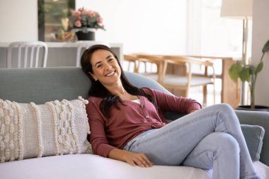 Mutlu bir Latin ev sahibinin portresi rahat bir kanepeye uzanmış ya da kiralık bir dairede gülümserken çağdaş ve şık bir oturma odasında rahat bir anın tadını çıkarıyor. Rahatlık ve refah