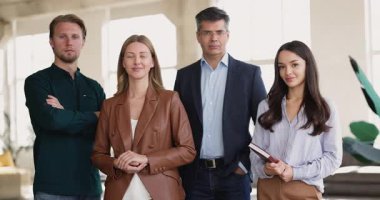 Gülümseyen iş adamlarından oluşan bir grup, kamera önünde yan yana duran şirket üyeleri, şirket yönetimini, birliği, başarıyı, işbirliği, ortak başarıları, ofis portresini temsil ediyor.