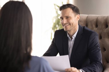 Mutlu erkek yönetmen, mülakatta iş adayı kadınla konuşuyor. Başvuruyu dostça gülümseyerek yapıyor. Elinde kağıt tutarak devam ediyor. İş danışmanı danışmanlık yapıyor.