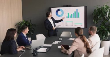 Toplantiya katılan kurumsal ekip finansal çizelgeleri sunuyor. Performans ölçümleri büyük ekranda. Uzmanlar verileri gözden geçirir, stratejiyi tartışır, brifing sırasında iş sonuçlarını değerlendirir