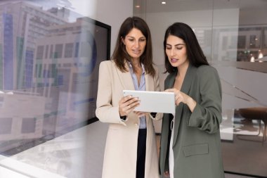 Tablet kullanarak, sunumu gözden geçirerek, iş raporlarını analiz ederek, mali verileri veya tabloları kontrol ederek, ortak görev tamamlamada işbirliği yaparak, projede birlikte çalışan iki çekici çok ırklı meslektaşım