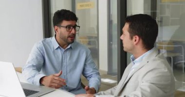 Ciddi genç Latin iş ortakları ofis masasında iş birliği, ortaklık, uzlaşma, anlaşma, el sıkışma, mutlu olma, gülümseme hakkında konuşuyorlar.