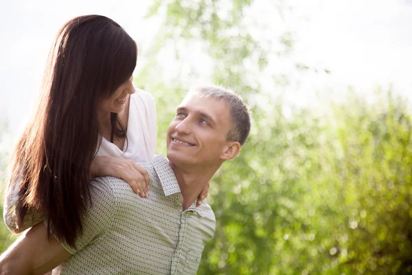 Young man carrying piggyback his girlfriend — Stock Photo, Image