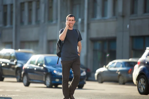 Young man on phone crossing street — Stock Photo, Image