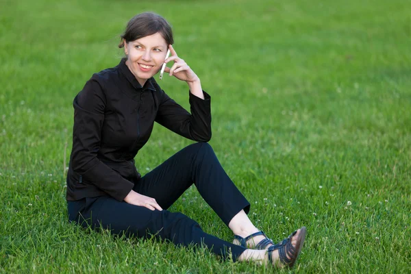 Young woman on phone sitting on grass