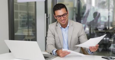 Olumlu yakışıklı bir yönetici satış raporlarını ve şirket gelirini analiz ediyor. Gözlüklü bir muhasebeci kağıt analizlerine bakıyor, dizüstü bilgisayar kullanıyor, gülümsüyor.