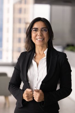 Çekici orta yaşlı bayan patronun portresi şık resmi kıyafetlerle kurumsal ofiste tek başına poz veriyor, kameraya bakıyor, profesyonellik, otorite ve başarı yayıyor. Liderlik, kariyer.