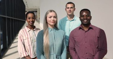 Çok uluslu ekip üyeleri, kameraya poz veren iş adamları, kurumsal çalışma alanında yan yana duran, yetkinlik yayan, birlik gösteren işadamları. İş yerinde takım çalışması, çeşitlilik ve profesyonellik