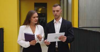 Ekip üyeleri ofis koridorunda yürürken işle ilgili sohbetlere öncülük ediyor, projeyi tartışıyor, fikir paylaşıyor ya da düşüncelerini paylaşıyor, iş jesti olarak el sıkışarak saygı gösteriyor, başarılı takım çalışması sonucu