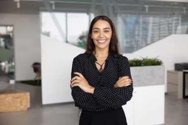 Kendine güveni tam genç bir Orta Doğulu yönetici kadın. Ofiste elleri bağlı poz veriyor. Kameraya bakıyor, vesikalık fotoğraf için bekliyor. Şirket sahibi, kadın CEO profesyonel portre