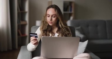 Evde elektronik alışveriş yapan genç bir kadın kredi kartı ve laptop kullanıyor, mal sipariş ediyor, internet sitesi veya pazar platformu üzerinden online alışveriş yapıyor. Güvenli e-banka sistemi, e-alışveriş.