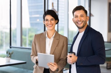 Dijital tablet ve kupalarla gülümseyen çok ırklı meslektaşlar, birlikte çalışma sırasında şirket portresi için poz vermek, başarılı bir işbirliği, takım çalışması ve iş ortaklığını temsil etmek.