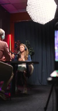 Canlı yayın sırasında mikrofonlarla masaya oturmuş dijital trendleri, çevrimiçi markalaşmayı profesyonel kayıt stüdyosunda kişisel deneyimi tartışan Podcast sunucusu sosyal medya etkileyicisi