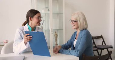 Kadın doktor teşhisi açıklıyor, tedavi planını paylaşıyor, kliniğe yaptığı ziyarette orta yaşlı kadın hastayla birlikte panodaki tıbbi test sonuçlarını inceliyor. Sağlık hizmetleri, tıbbi danışmanlık