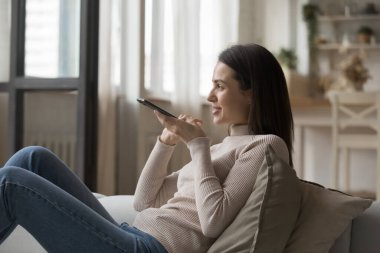 Cep telefonu tutan genç çekici bir kadın hoparlörde hoş sohbetler yapıyor. Kanepede yalnız başına dinleniyor, bilgi arıyor sanal asistanı kullanıyor, yeni gündem yaratıyor, uygulamalar kullanıyor. Modern teknoloji konsepti