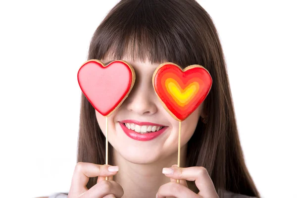 Happy woman playing with heart shaped biscuits — Stock Photo, Image