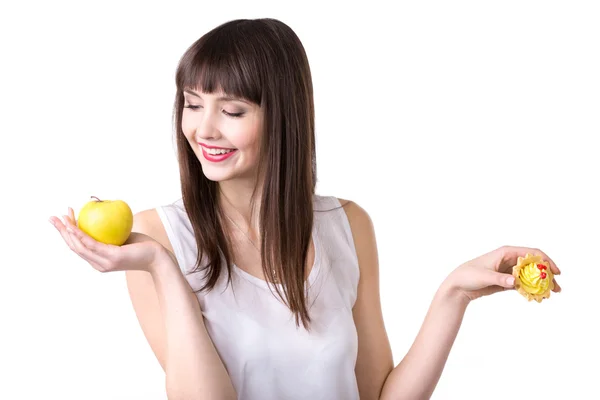 Young woman choosing apple instead of cake — Stok fotoğraf