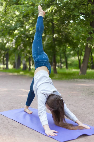 One-legged down dog yoga pose in park alley — Stock Photo, Image