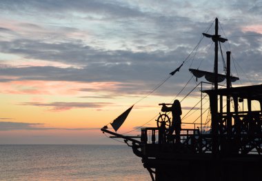 Silhouette of a pirate ship at sunset clipart