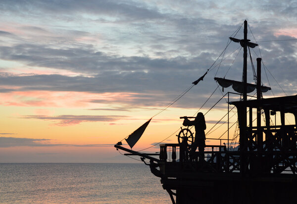 Силуэт пиратского корабля на закате
