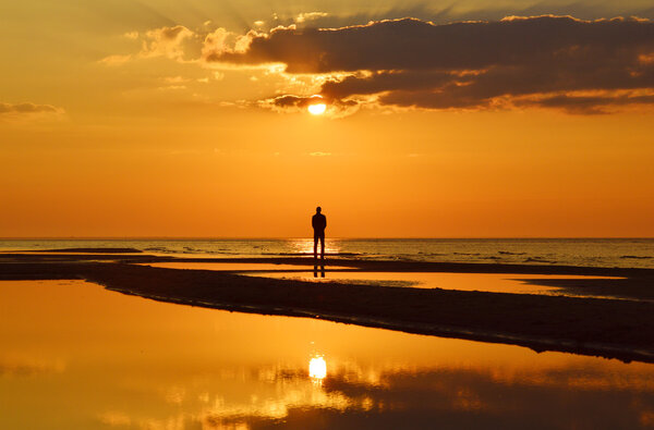 Silhouette of a man watching sunset on a seashore