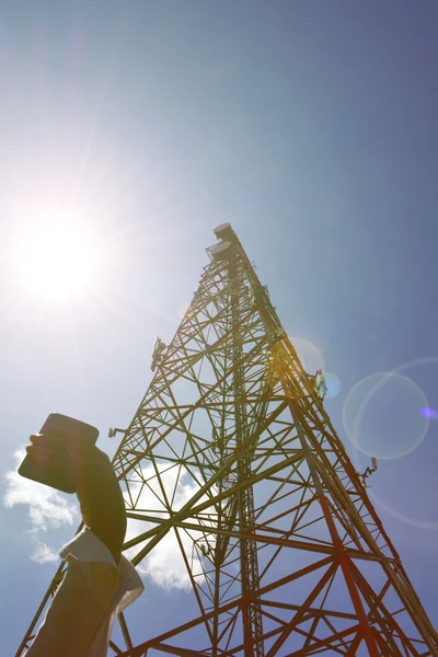 Mulher com smartphone perto da torre de telecomunicações — Fotografia de Stock