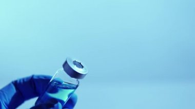 Aşı ve bulaşıcı hastalıklar konsepti geliştiriyor. Coronavirus, COVID-19 'a karşı mavi ilaçlı steril ilaç tutan doktor. Klinik deneyler insan tasviri üzerinde geliştirme ve test.