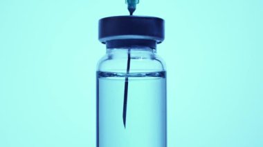 Şırıngayı şişeden aşıyla dolduruyorum. Aşırı makrodan. Steril tıbbi iğne şırıngası ve tıbbi klinikteki hasta aşısı için mavi koronavirüs aşısı ile ilaç veriliyor..