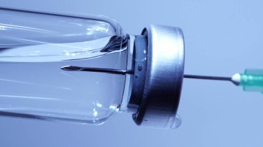 Şırıngayı şişeden aşıyla dolduruyorum. Aşırı makrodan. Steril tıbbi iğne şırıngası ve Coronavirus aşısı ile ilaç tedavisi klinikteki hasta aşısı için.  