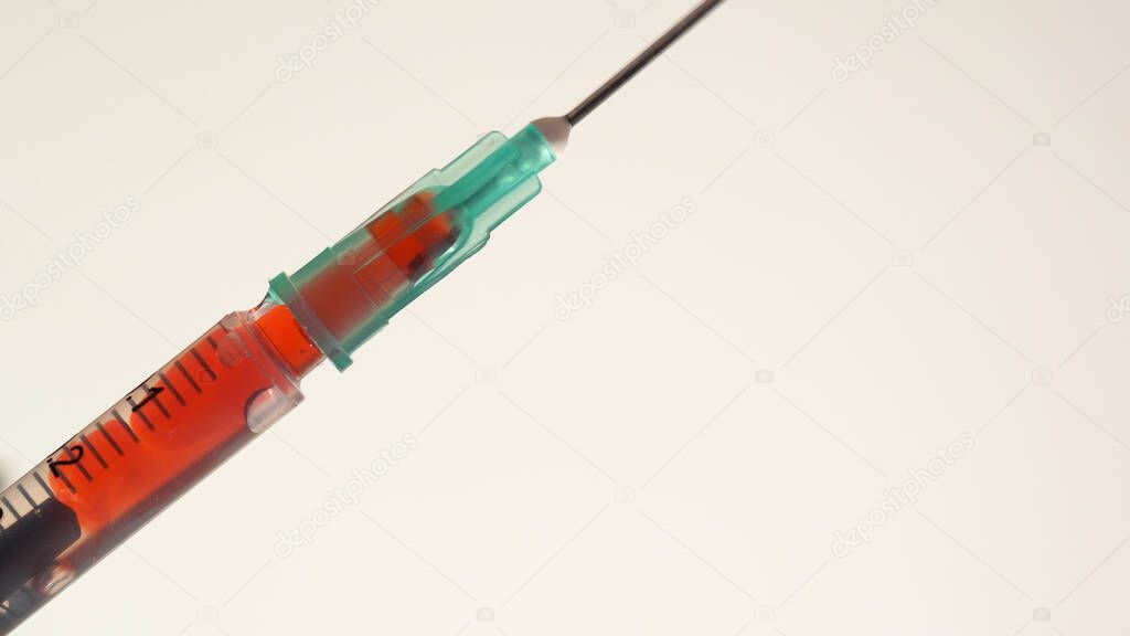 Syringe close up taking mixing blood of a patient with drug and injection. Saline solution mixing with liquid blood. Medical procedure and administration of supervised opioid treatment.