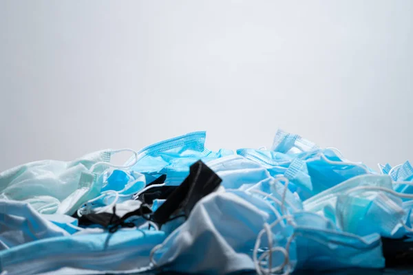 Medical masks on the table. Pile of used personal protective equipment PPE. Pollution by surgical masks during the coronavirus pandemic. A lot of Covid-19 plastic waste and garbage, disposable masks.