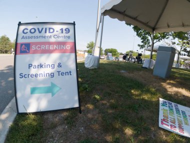 Covid-19 Assessment Centre Screening Parking and Screening Tent sign near hospital in the city. Coronavirus test for workers due pandemic. The fight with virus and second wave control.  clipart