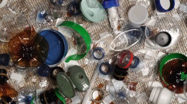 Evdeki plastik çöpler masanın üzerinde. Atıklar atıldı, denizciden toplandı. Plastikten yapılmış şehir çöplüğü. Boş şişe ve bardaklar çevresel kirlilik ve ekolojik sorun yaratıyor.
