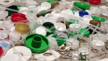 Plastik şişe parçaları, bardaklar, mantarlar, pipetler, su ve şampuan şişeleri, krem ambalajlar ve masaya atılan diğer bir kerelik çöpler. Çevre kirliliği, geri dönüşüm, atık yönetimi sorunu.