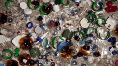 Plastik şişe parçaları, bardaklar, mantarlar, pipetler, su ve şampuan şişeleri, krem ambalajlar ve masaya atılan diğer bir kerelik çöpler. Çevre kirliliği, geri dönüşüm, atık yönetimi sorunu.