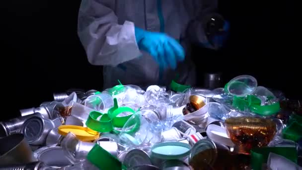 Ein Mann sortiert Plastik- und Metallmüll am Förderband einer Recyclinganlage. Müll- und Müllsortieranlage. Plastikmüll überproduziert und schädigt die Umwelt, Bedrohungen für die Tierwelt. — Stockvideo