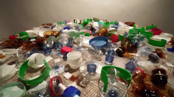 Пластиковая куча мусора из домашнего хозяйства, собранная на столе. Одноразовое или одноразовое использование отходов. Городской мусор из пластика. Пустые использованные бутылки и чашки создают загрязнение окружающей среды. — стоковое видео