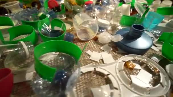 テーブルの上に集められた家庭からのプラスチックごみの山。廃棄物は一回限りまたは一回のみ使用します。プラスチック製の都市ホームゴミ。空の使用済みボトルやカップは環境汚染を作成します. — ストック動画