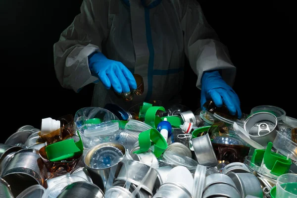 Volunteer cleaning, sorting pile of plastic and metal tin. Collecting, separating one time use plastic trash from aluminum cans. Pollution and environmental problem with household waste management.