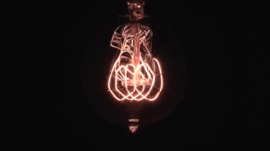 Edison ampulü yavaş yavaş odak ve detaylarla ortaya çıkar. Vintage filament ampulün altında kayarak alttaki makro görüntüyü bokeh efektiyle parlıyor ve parlatıyor. 4K.