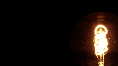 Edison retro ampulünün yavaş dönüşü. Dönen vintage iplik tungsten ampul fikir görünümünü ortaya koyuyor. Sıcak nostaljik gece yatak odası makro yakın çekim konsepti. 4k.