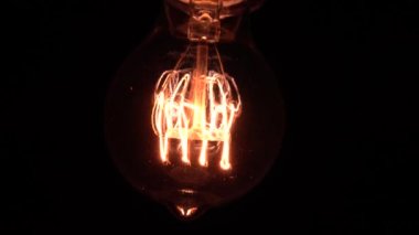 Edison ampulü yavaş yavaş odak ve detaylarla ortaya çıkar. Vintage filament ampulün altında kayarak alttaki makro görüntüyü bokeh efektiyle parlıyor ve parlatıyor. 4K.
