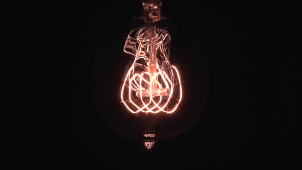 Lâmpada Edison lentamente revelar em foco e detalhes. Deslizando sob lâmpada de filamento vintage brilhando e iluminar vista macro close-up de baixo com efeito bokeh. 4K. — Vídeo de Stock